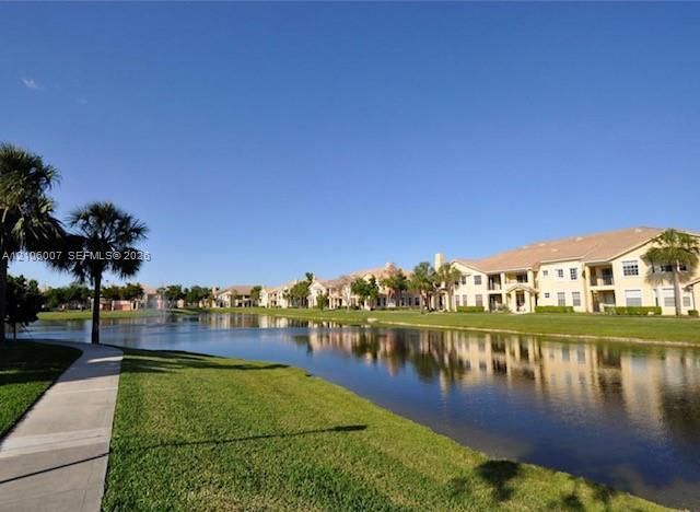 Waterfront community featuring a paved walking path, manicured lawn, and mature palm trees