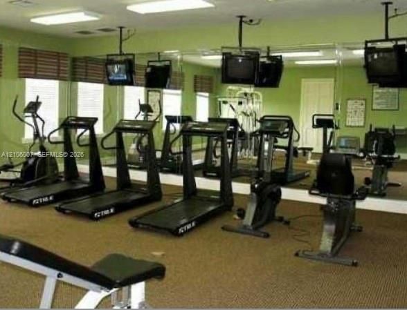 Fitness room featuring floor-to-ceiling wall mirrors, recessed overhead lighting, and window blinds