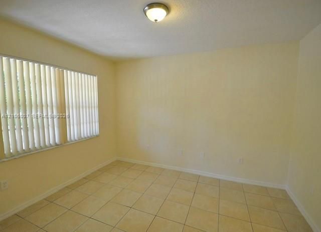 Neutral-toned tile flooring, large windows with vertical blinds, and a central ceiling-mounted light fixture