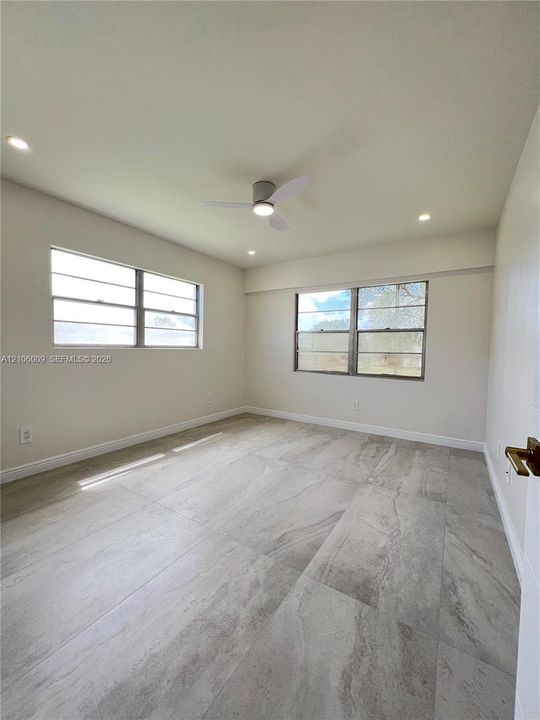 Neutral-toned room featuring large-format tile flooring, recessed lighting, and a modern ceiling fan with an integrated light fixture
