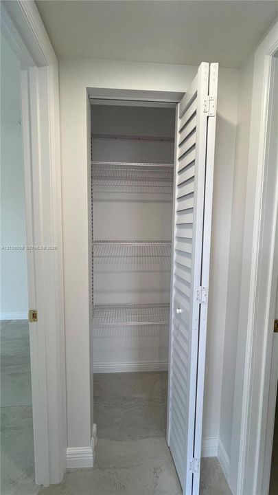Storage closet featuring white louvered bifold doors and integrated wire shelving