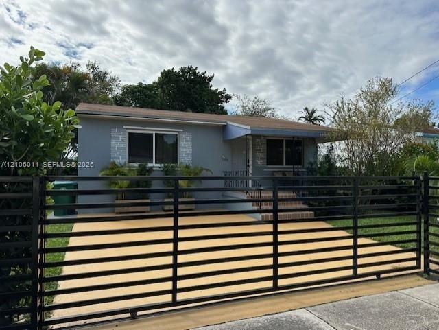 Single-story exterior featuring a horizontal slat metal gate, paved driveway, stone-veneer accents, and a covered entryway