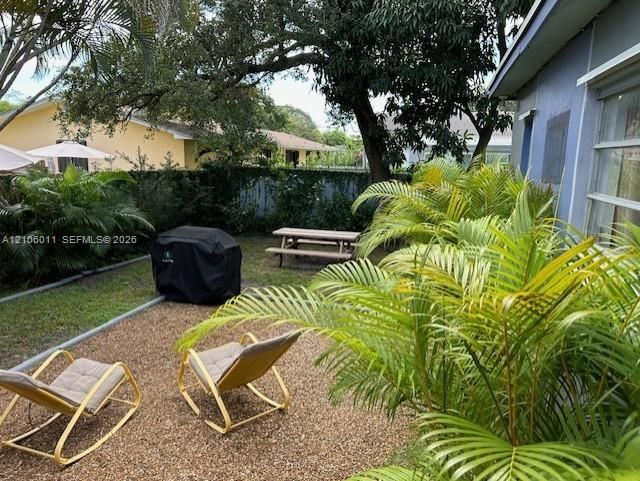 Private backyard featuring pea gravel ground cover, mature landscaping, and an enclosed perimeter fence