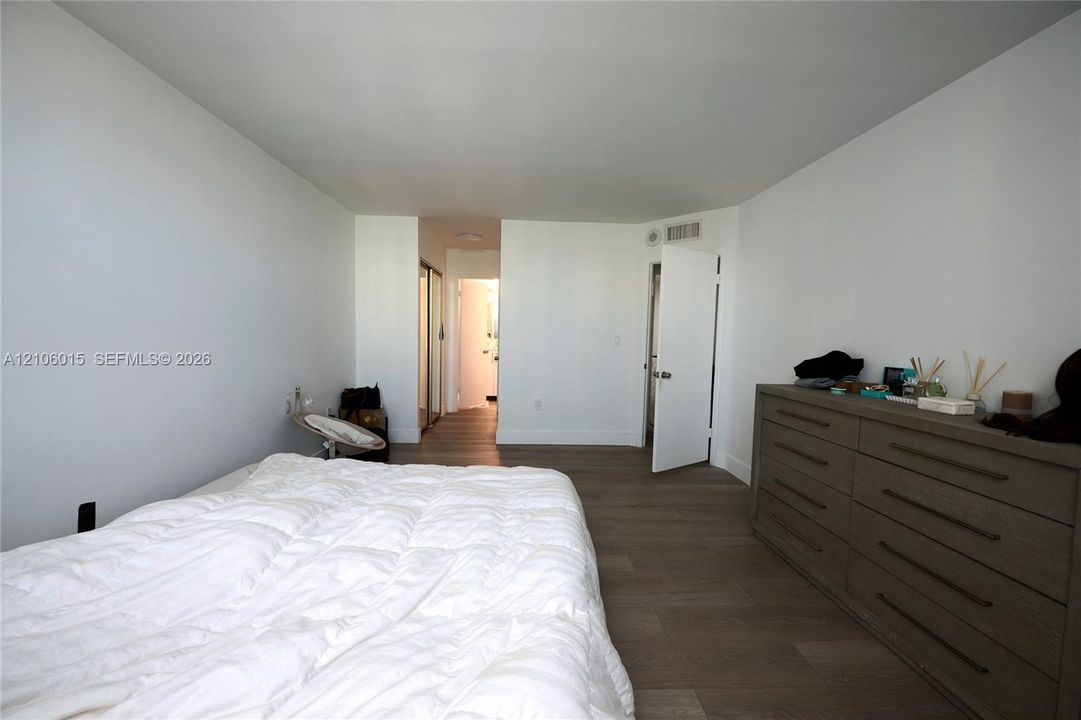 Neutral-toned wood-finish flooring, white walls, and closet with mirrored sliding doors
