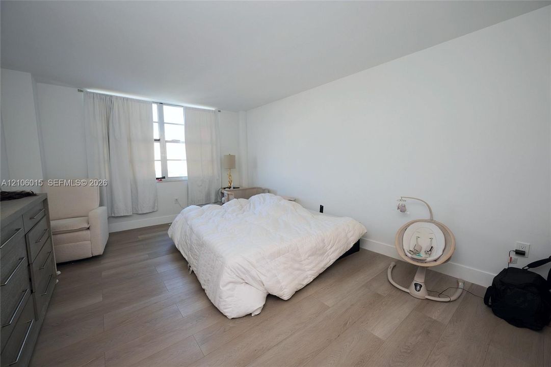 Neutral interior featuring wood-finish flooring, white walls, and a large multi-pane window