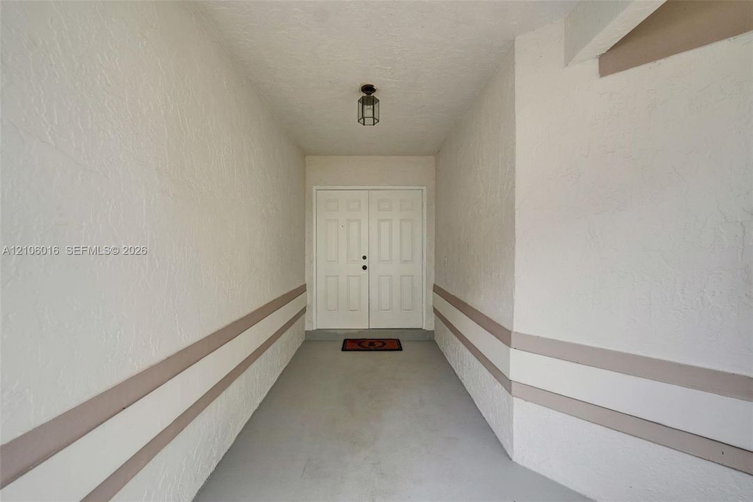 Covered entryway featuring double entry doors, textured wall finishes, and overhead lantern-style lighting