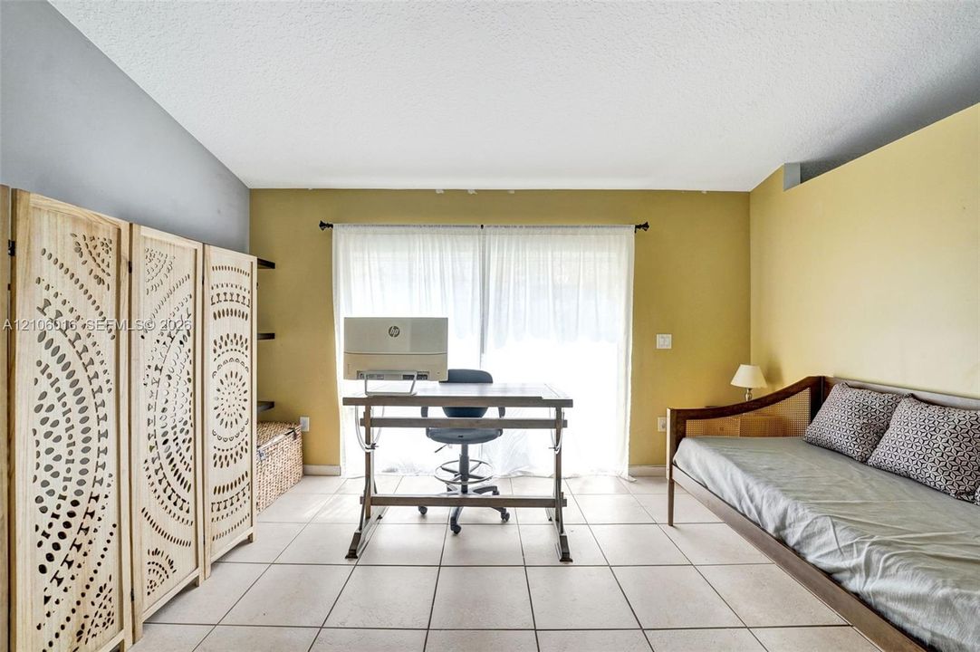 Spacious room featuring neutral ceramic tile flooring and sliding glass doors with overhead curtain rod hardware