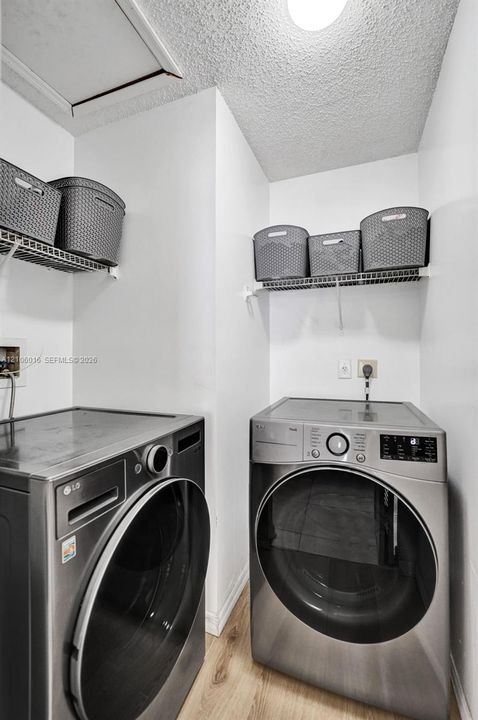 Dedicated laundry area featuring wire shelving and wood-finish flooring
