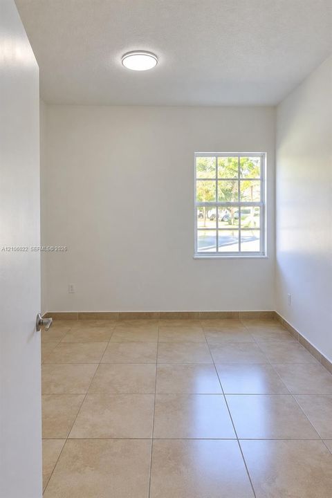 Neutral interior space featuring ceramic tile flooring, a multi-pane window, and a flush-mount ceiling light fixture