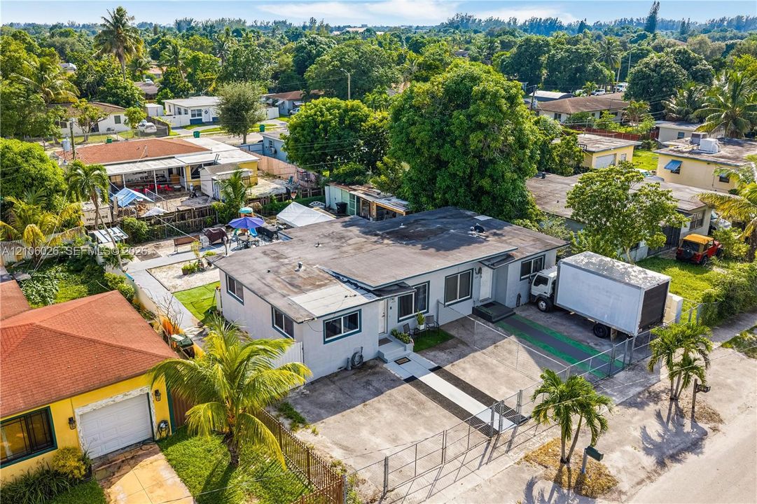 Single-story residence featuring a concrete driveway, metal perimeter fencing, and established tropical landscaping