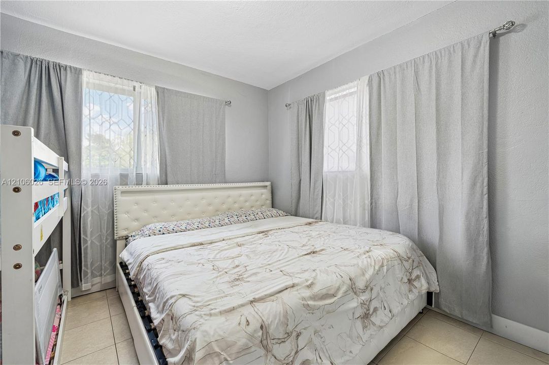 Room featuring light-toned tile flooring, neutral wall finishes, and two windows with diamond-patterned grid detailing