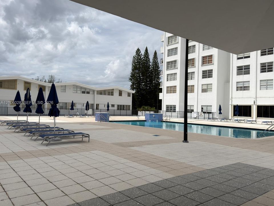 Outdoor swimming pool area featuring a rectangular basin with tile deck surround and metal perimeter fencing