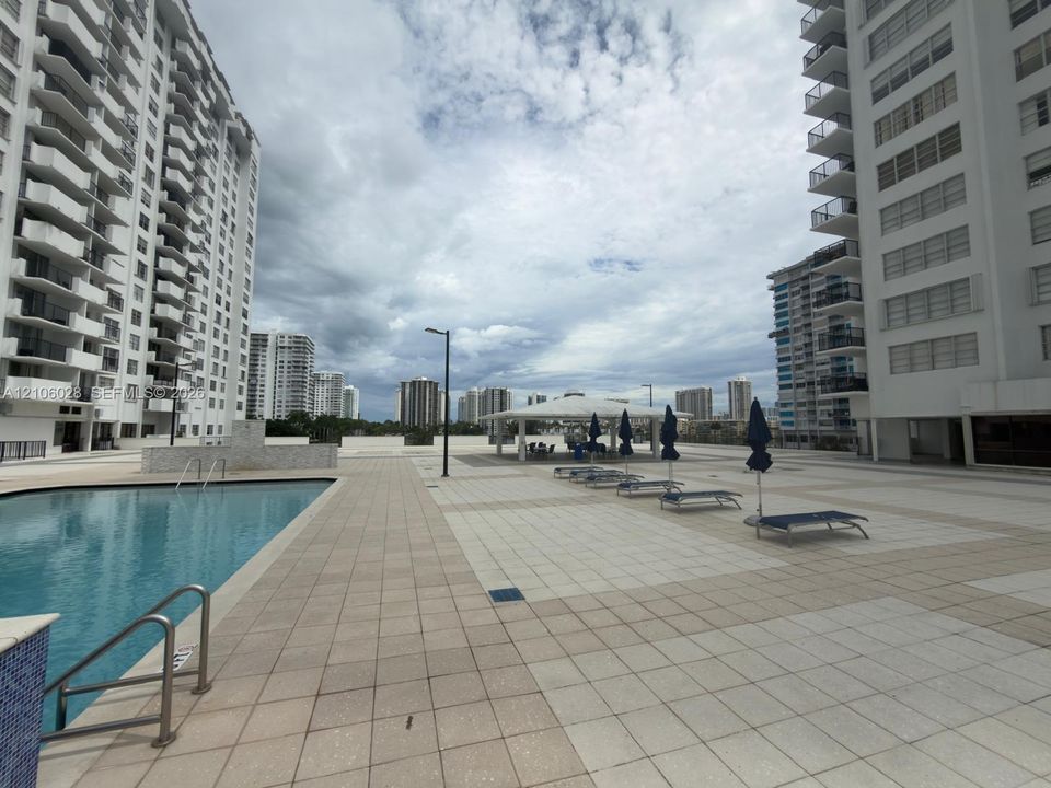 Outdoor pool with tiled surround, stone-clad water feature, and covered pavilion area