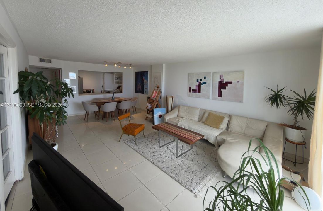 Open-concept living space featuring large-format tile flooring, a pass-through wall opening, and recessed ceiling track lighting