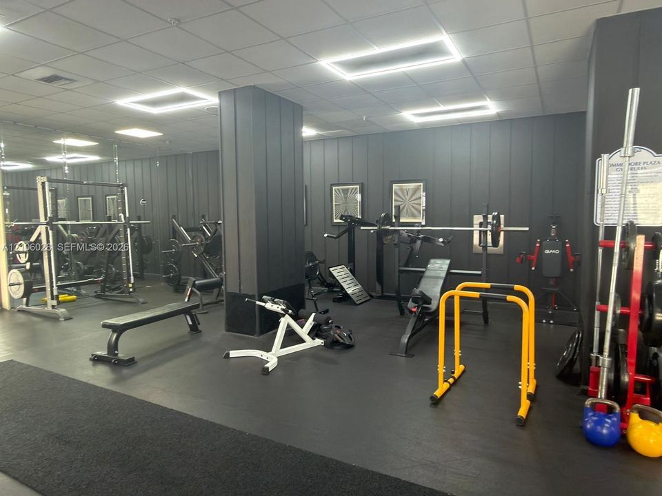 Fitness center featuring wall-to-wall mirrors, vertical panel wall cladding, and rubberized flooring