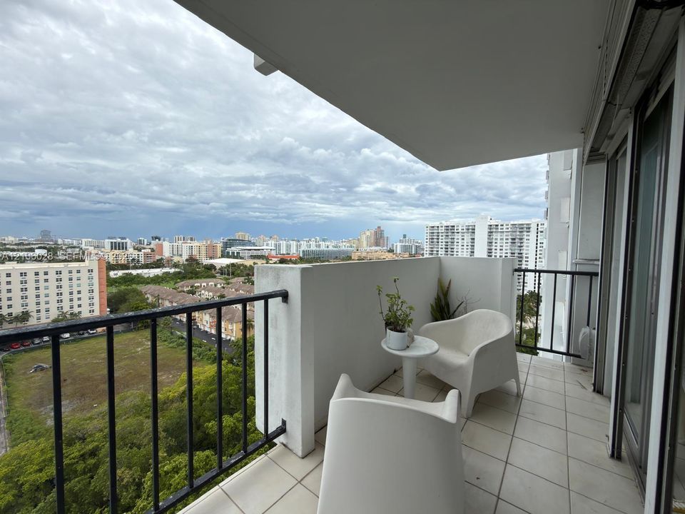 Covered balcony featuring white tiled flooring and black metal railing