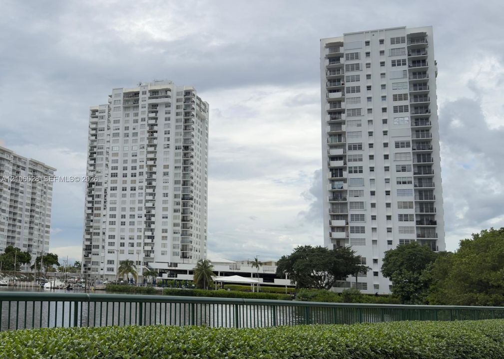 High-rise residential towers featuring multiple private balconies, floor-to-ceiling windows, waterfront positioning, and landscaped perimeter greenery