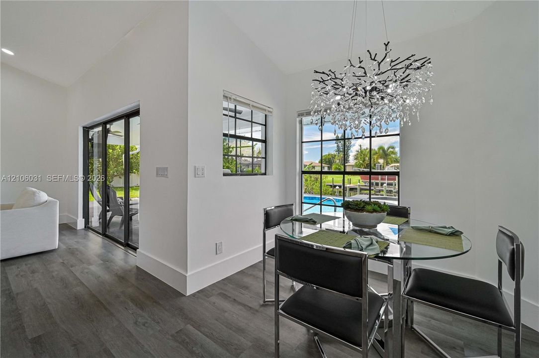 Wood-finish flooring, floor-to-ceiling grid windows, sliding glass door, and decorative branching chandelier