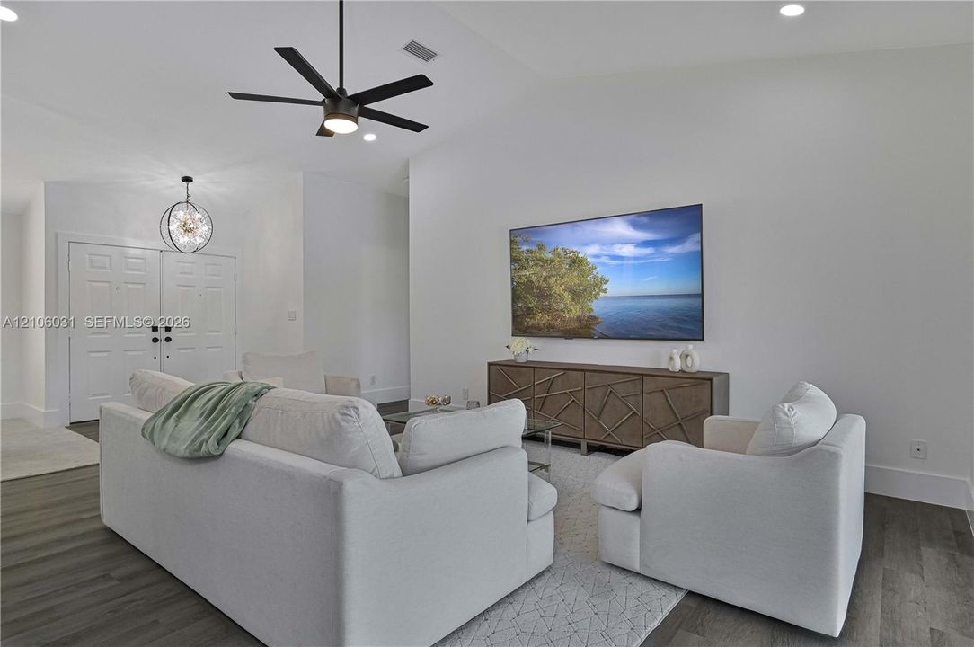 Vaulted ceilings, wood-finish flooring, multi-blade ceiling fan, orb-style pendant lighting, and double-door entry