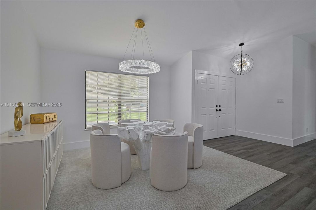 Dual-tone interior featuring wood-finish flooring, a contemporary crystal ring chandelier, a spherical pendant light, multi-pane window, and double-entry doors