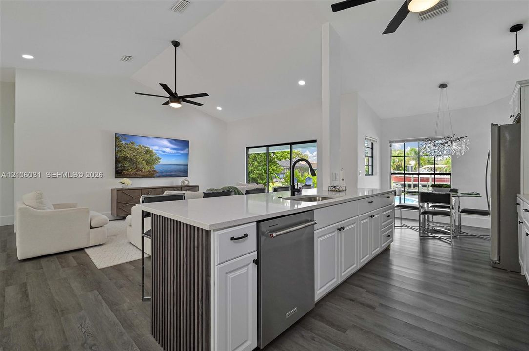 Kitchen island featuring a stone-surface countertop, slatted wood-finish detailing, stainless steel dishwasher, and matte black hardware