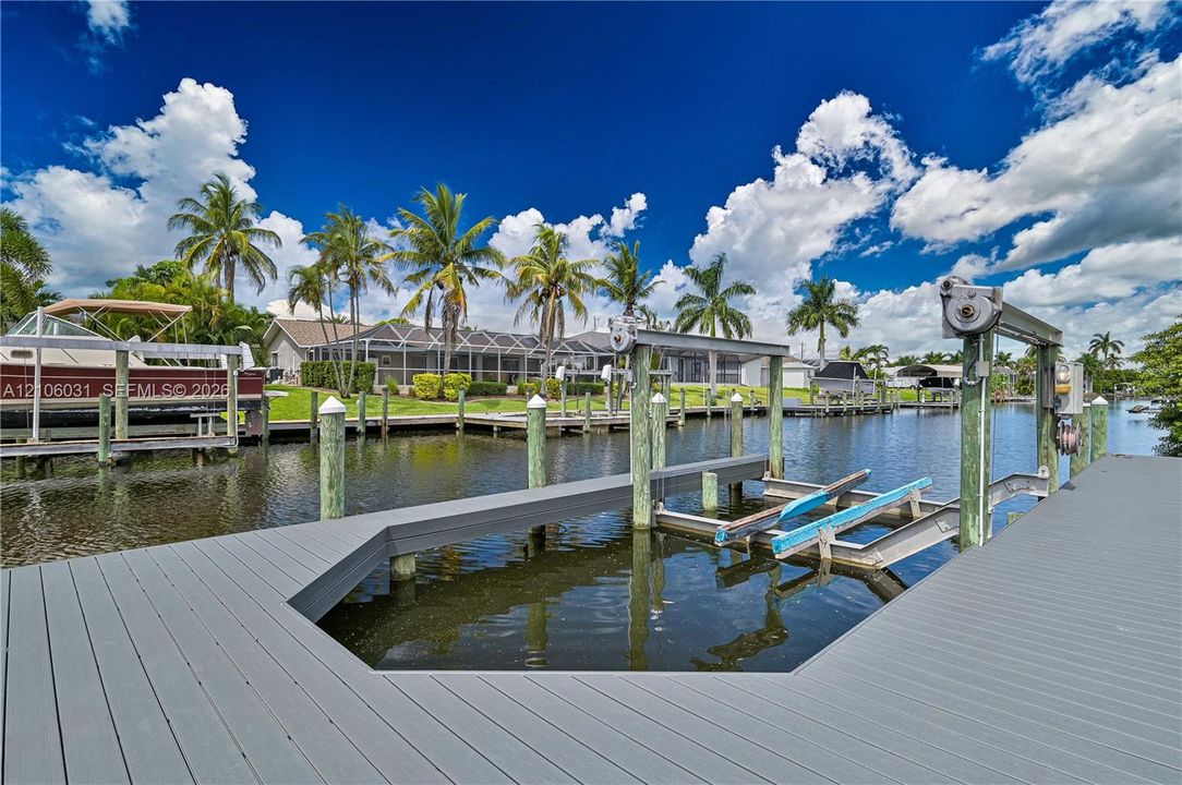 Private boat dock featuring a heavy-duty mechanical boat lift, composite decking, and direct canal access