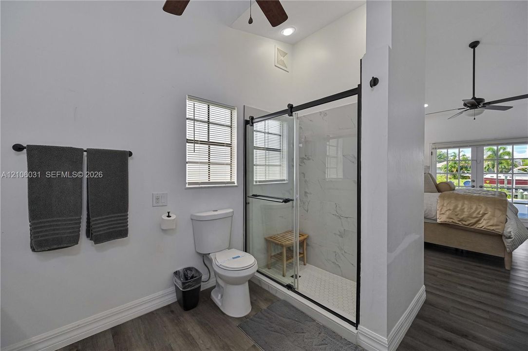 Walk-in shower featuring a frameless glass enclosure, matte black hardware, and stone-finish wall tile