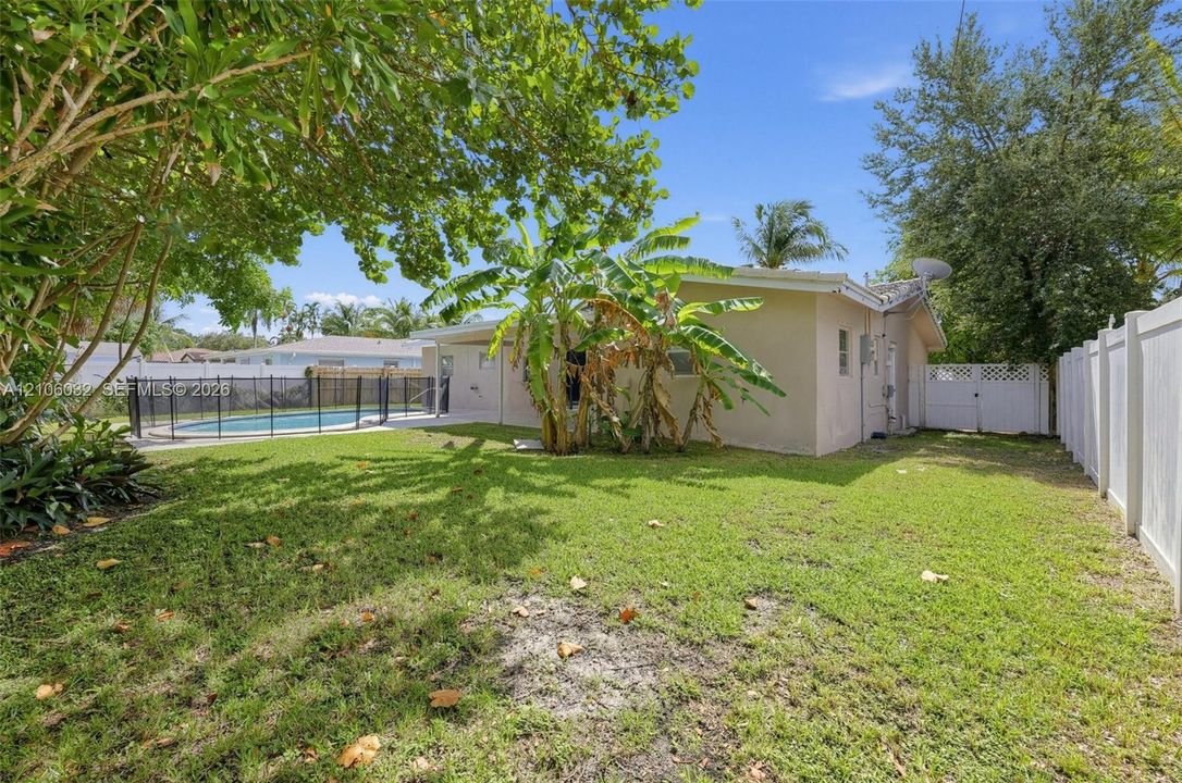 Private backyard featuring an in-ground swimming pool, perimeter vinyl privacy fencing, metal pool enclosure, and mature landscaping