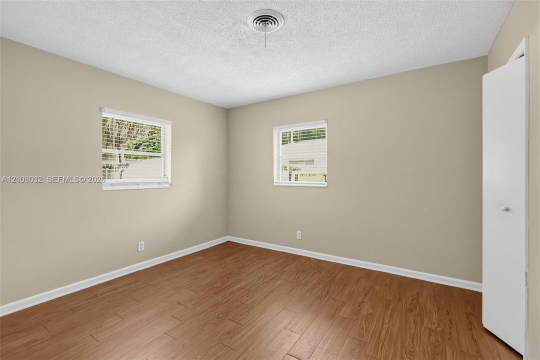Neutral wall tones, wood-finish flooring, two dual-pane windows, and a built-in closet with a white panel door