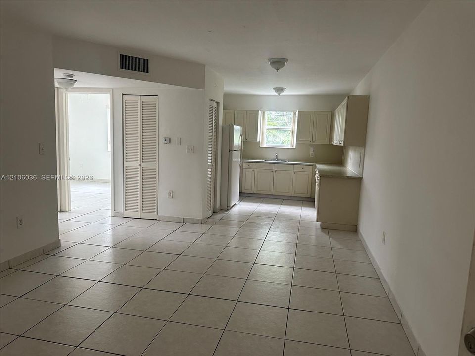 Kitchen featuring cabinetry with neutral finish, tile flooring, and integrated white appliances