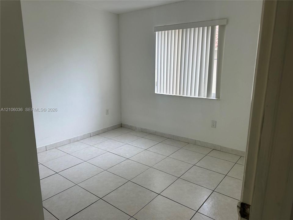 Neutral interior featuring light-colored square tile flooring and vertical blinds