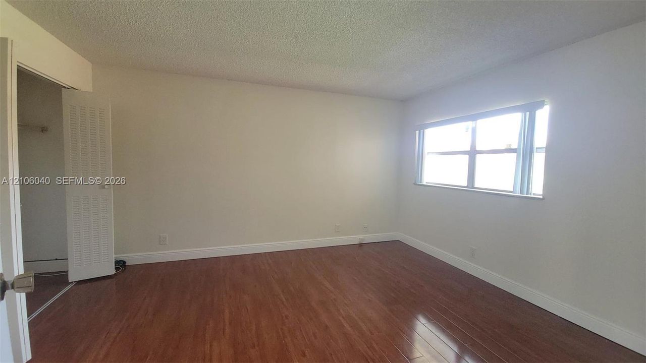 MASTER BDR Interior space featuring wood-finish flooring, a horizontal window, and a built-in closet with louvered doors
