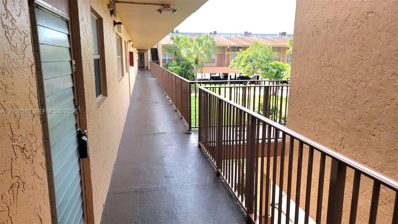NORTH facing unit entry door featuring integrated jalousie glass panels, metallic hardware, and a stucco-textured exterior finish