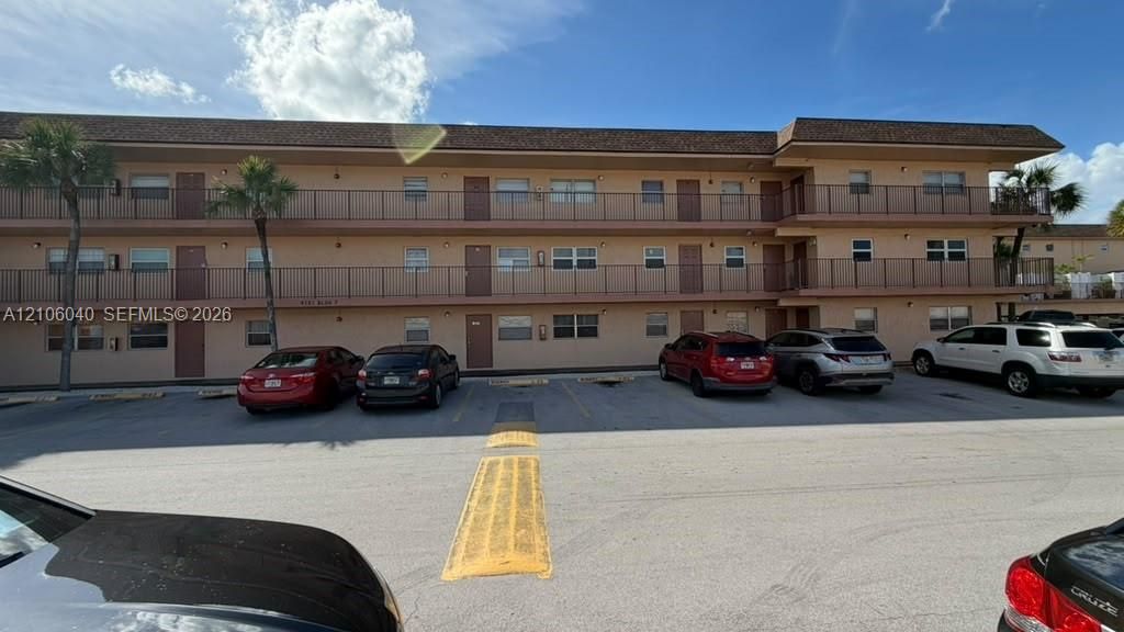 BLDG 6 Three-story multi-unit structure featuring a shingled roof, exterior balconies with metal railings, and surface parking