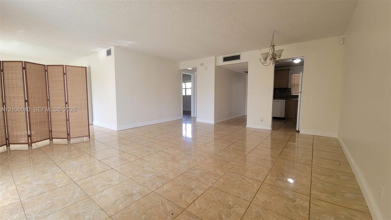 LIVING-DINING Open-concept room featuring light-toned tile flooring, neutral wall paint, and a multi-arm ceiling-mounted light fixture