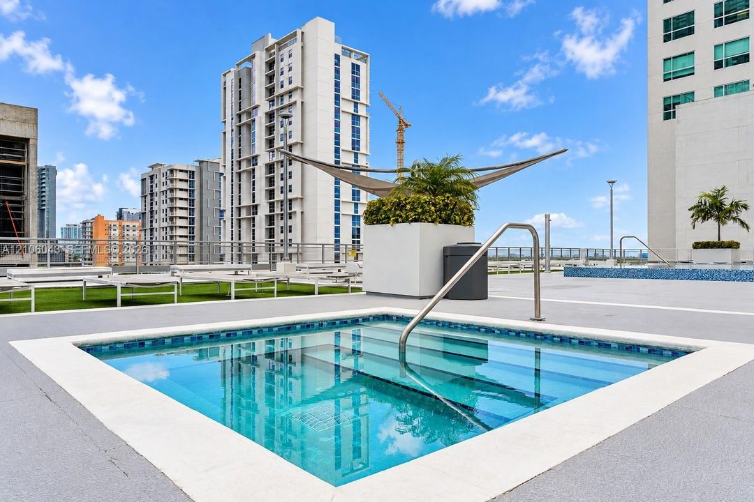 Rooftop spa with tile lining, stainless steel handrails, custom shade structure, and surrounding synthetic turf