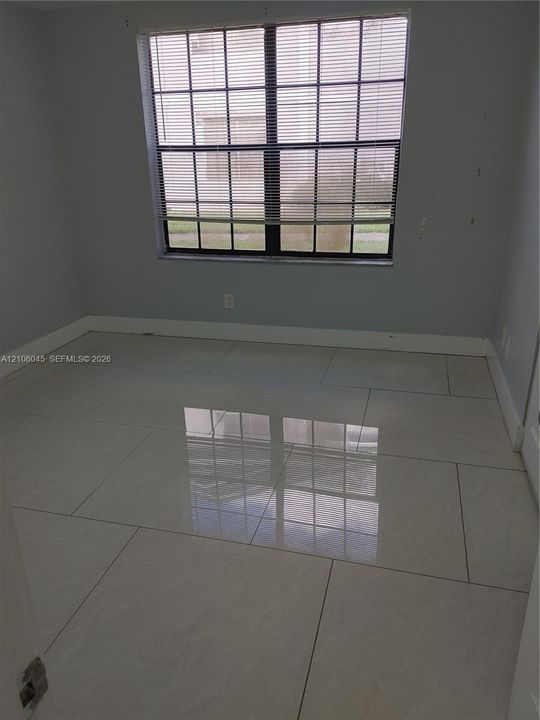 Large-format polished tile flooring, neutral wall tones, and a multi-pane window featuring integrated window blinds