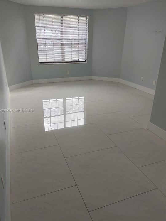 Neutral-toned room featuring large-format polished tile flooring and a multi-pane window