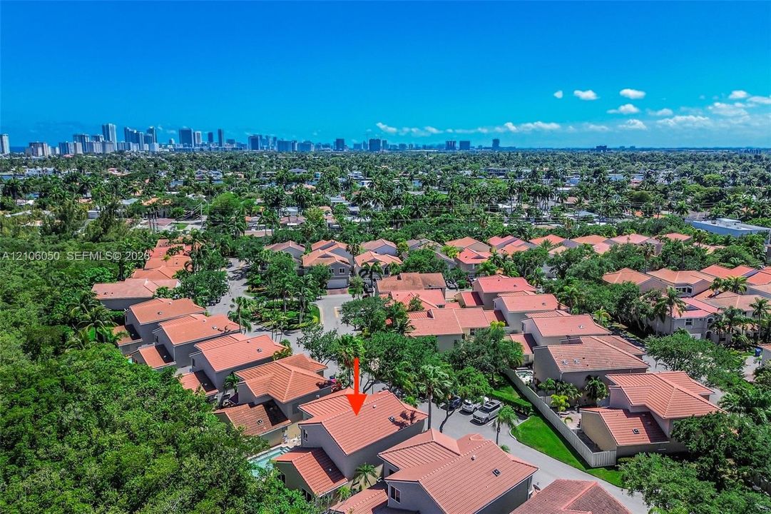 Aerial perspective of a multi-story residence featuring a terracotta tile roof and an in-ground swimming pool, situated within a suburban residential community
