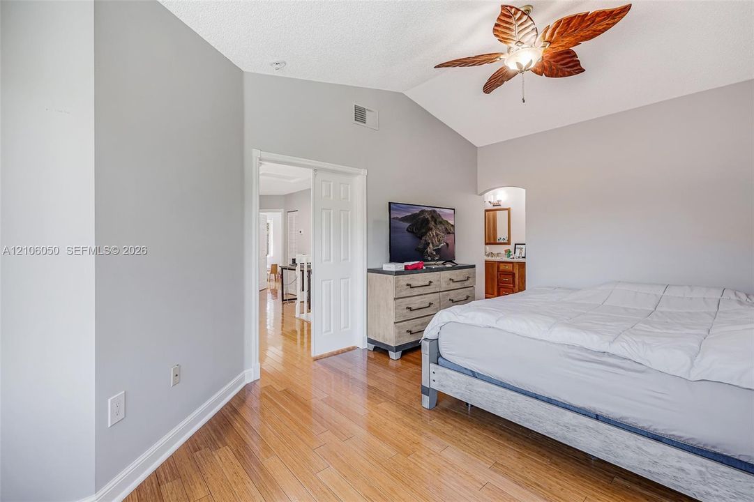 Vaulted ceilings, wood-finish flooring, and a decorative leaf-style ceiling fan