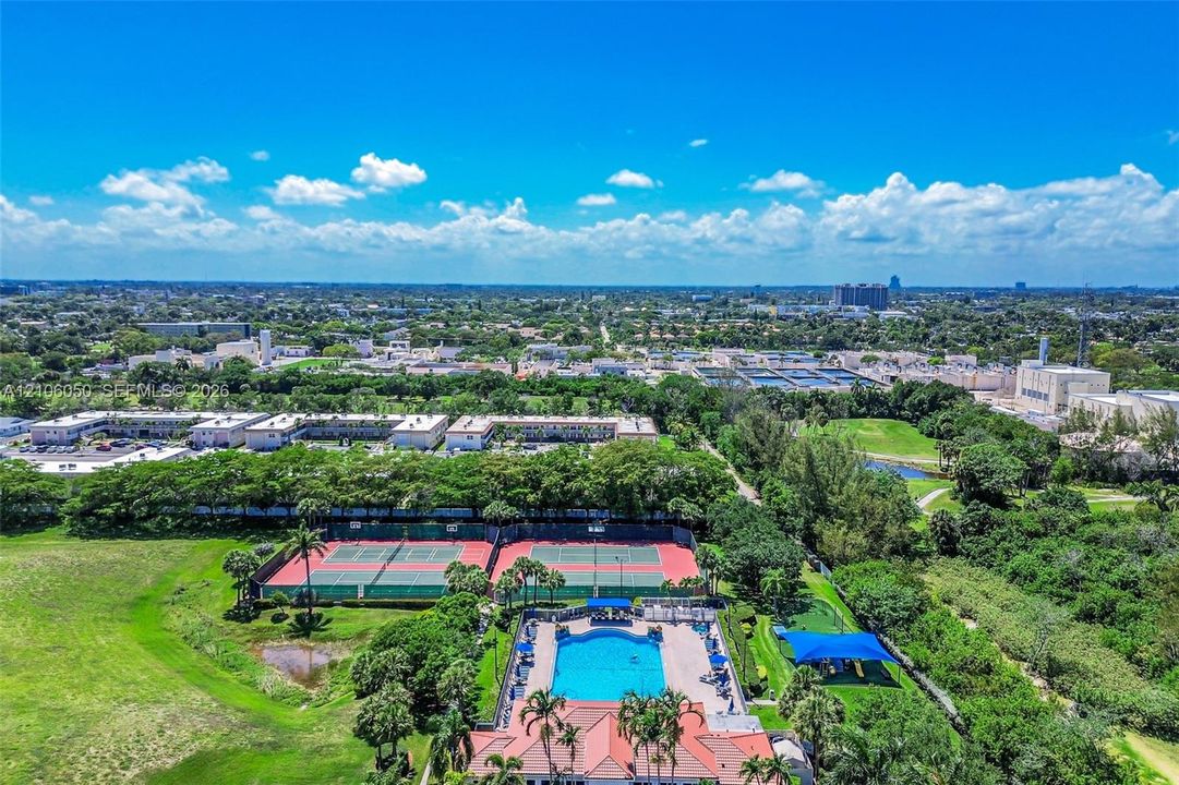Recreational facilities featuring two hard-court tennis courts, a swimming pool with paved deck, and a shaded structure