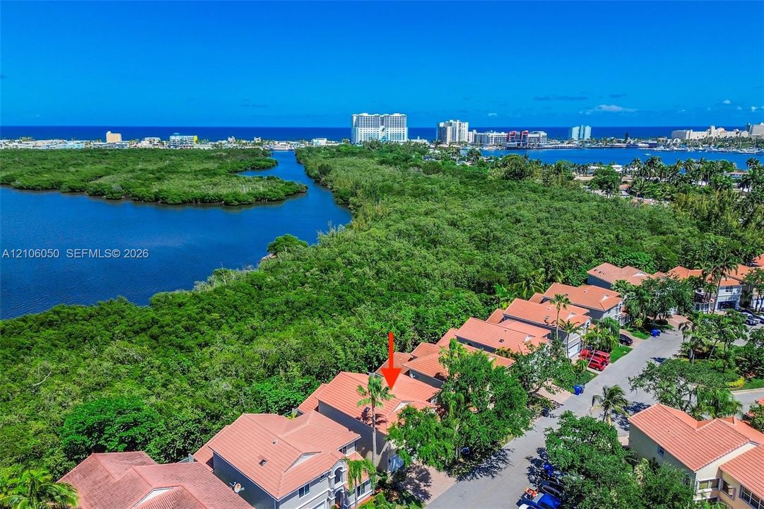 Aerial perspective featuring tile-roof residential construction and proximity to coastal waterways and dense natural vegetation
