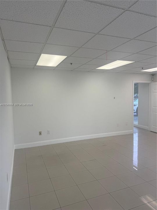 Neutral-toned ceramic tile flooring, drop ceiling with recessed rectangular lighting, and smooth-finished walls