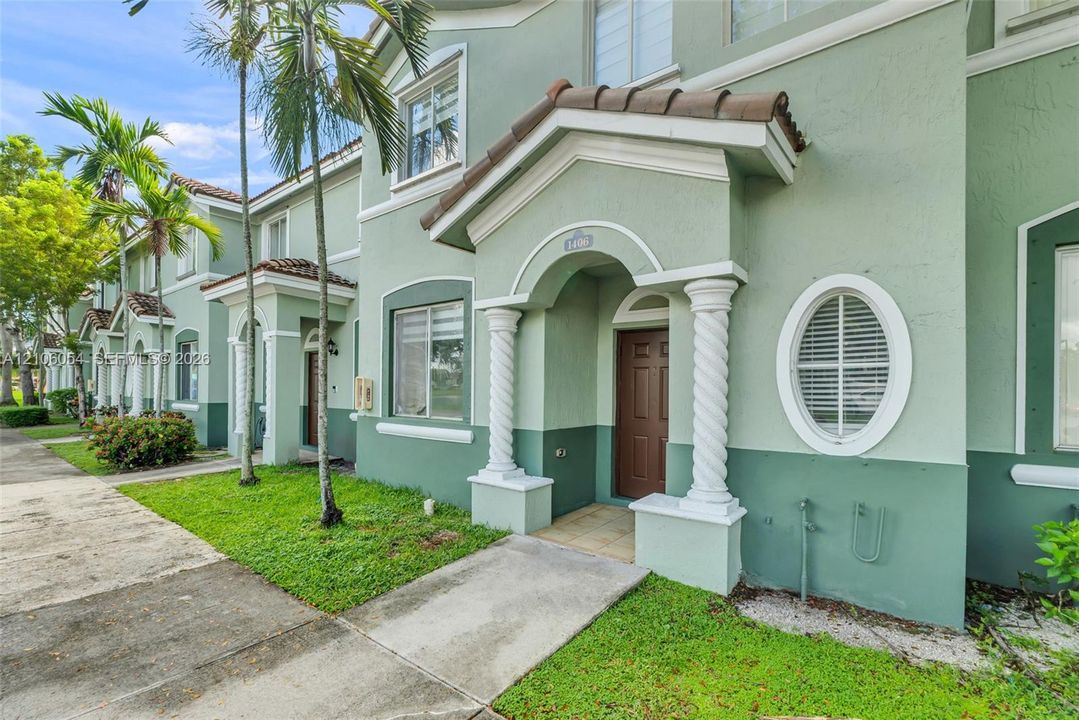 Stucco exterior featuring dual-tone paint, a covered entrance with spiral columns, and a decorative oval window