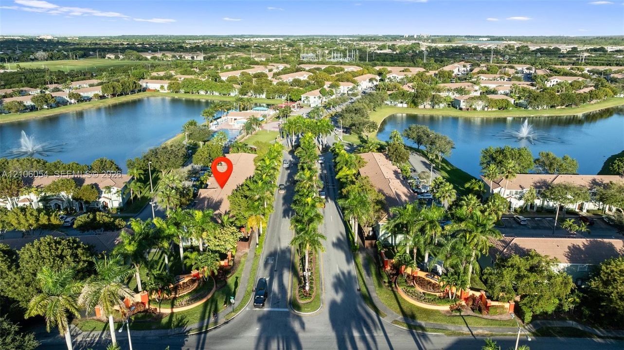 Aerial perspective of a multi-unit community featuring terracotta-tiled roofs, mature palm landscaping, and large water features