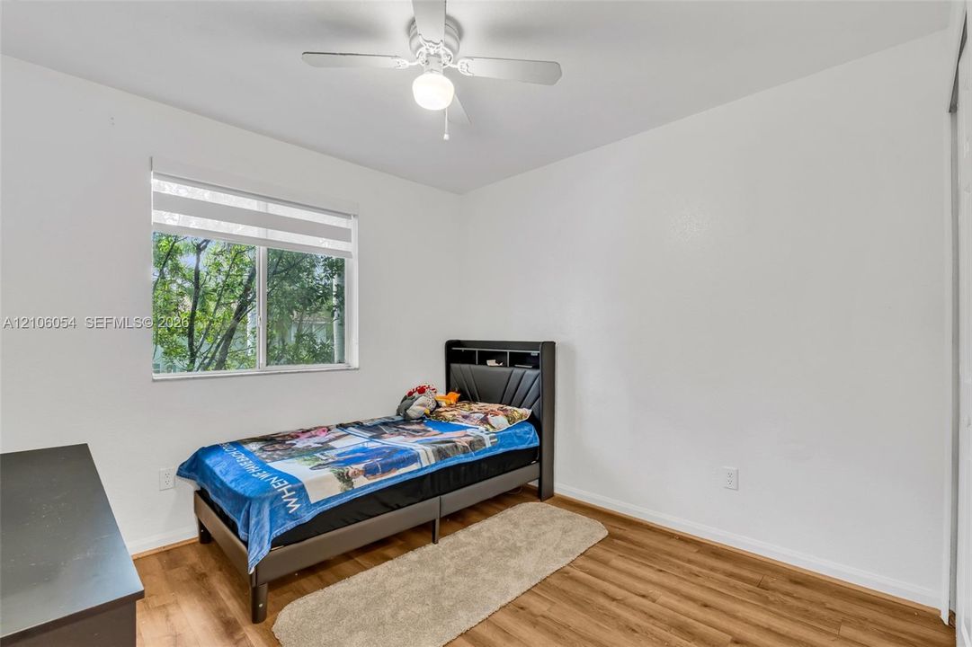 Wood-finish flooring, multi-pane window, and white ceiling fan with integrated lighting