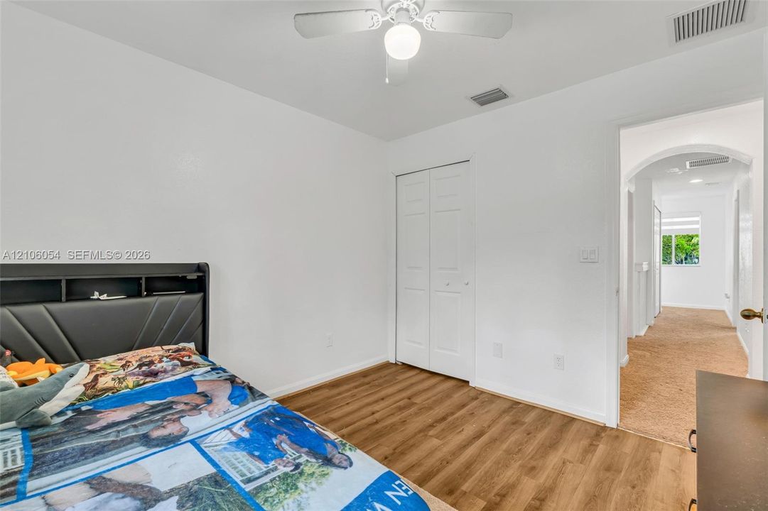 Wood-finish flooring, ceiling fan with integrated lighting, and white bi-fold closet doors
