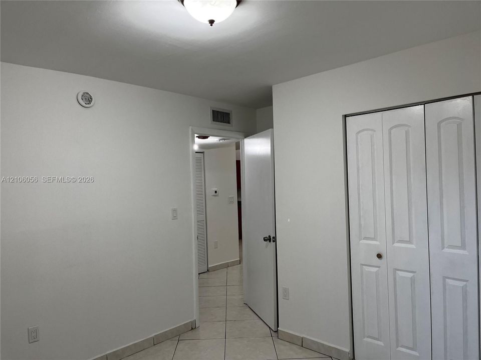 Interior space featuring tile flooring, neutral wall tones, bi-fold closet doors, and overhead flush-mount lighting