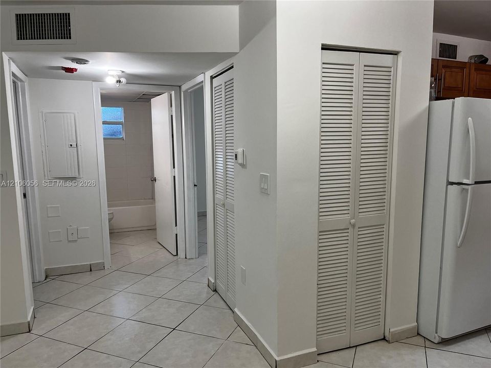 Interior hallway featuring neutral ceramic tile flooring and two sets of louvered-door closets