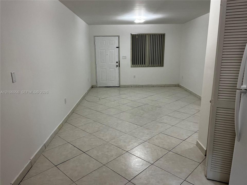Interior space featuring diagonal tile flooring, a multi-panel entry door, and vertical window blinds